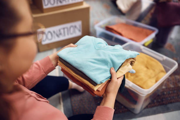 istock Close-up of volunteer packing clothes into donation boxes. 1388313433