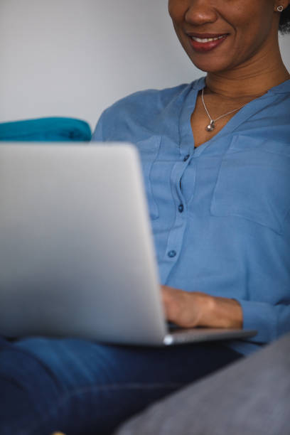 istock Smiling woman relaxing on the sofa and using laptop for fun 1388314054