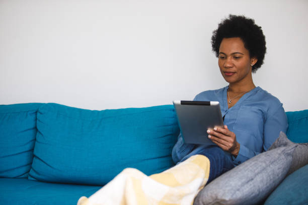 istock Happy mid adult woman resting on the sofa and using digital tablet 1388314064