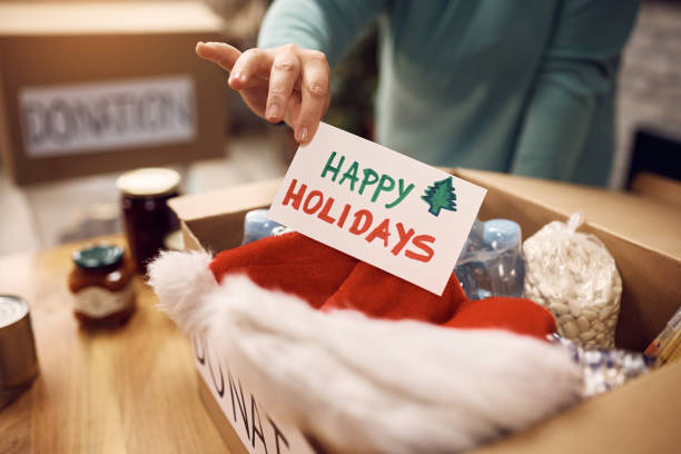 zbliżenie wolontariusza dodającego kartkę z życzeniami świątecznymi do doksu darowizny. - giving christmas lifestyles holiday zdjęcia i obrazy z banku zdjęć