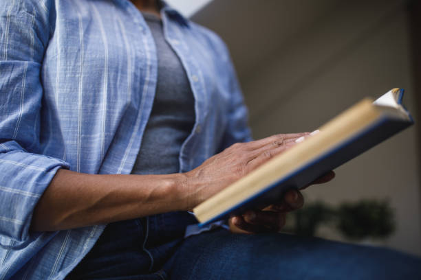 Midsection of unrecognizable African American woman holding and reading an interesting book.