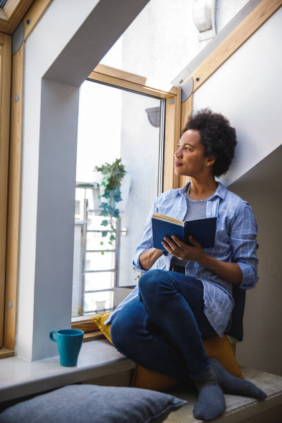 istock Woman looking out the window and contemplating while reading a book 1388314203