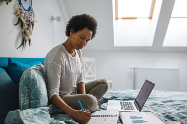 istock Woman working remotely from her bedroom, writing plans and ideas 1388314628
