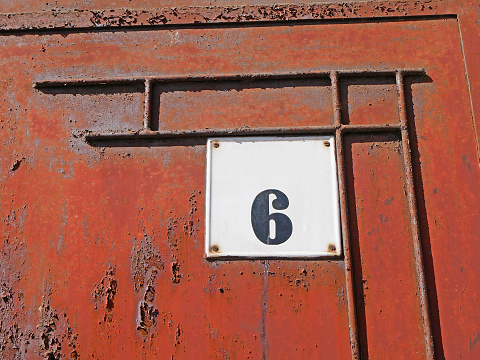 Old rusty metal door with number plate
