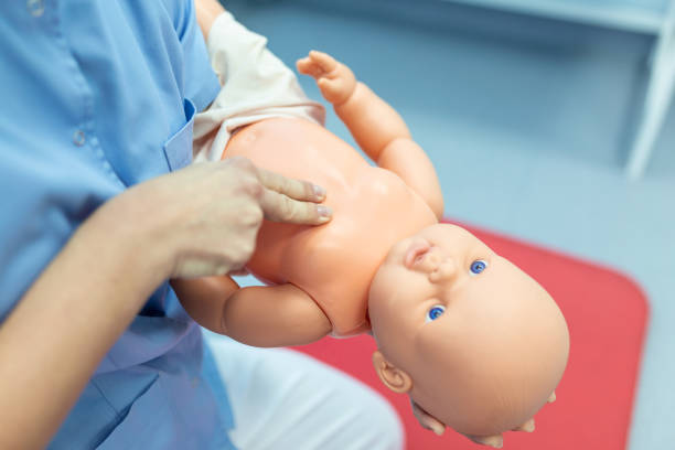 istock Woman performing CPR on baby training doll with one hand compression. First Aid Training - Cardiopulmonary resuscitation. First aid course on cpr dummy. 1388321296