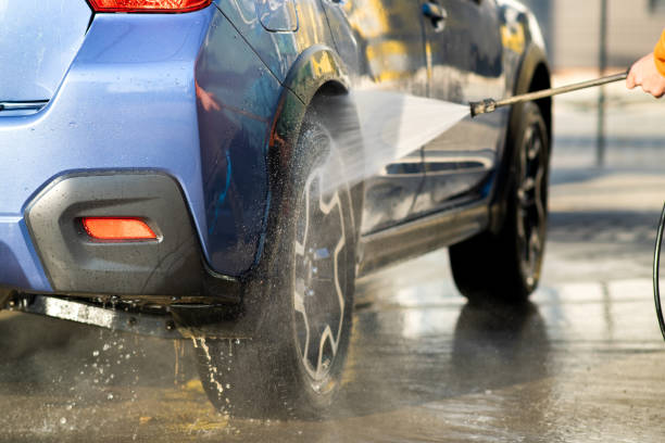 Closeup of male driver washing his car with contactless high pressure water jet in self service car wash. Closeup of male driver washing his car with contactless high pressure water jet in self service car wash. car wash stock pictures, royalty-free photos & images