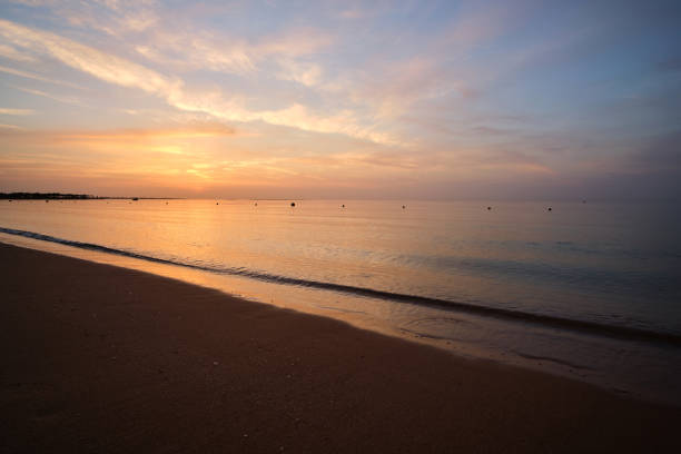istock Calm sea shore with crushing waves on sandy beach at sunrise. 1388321995