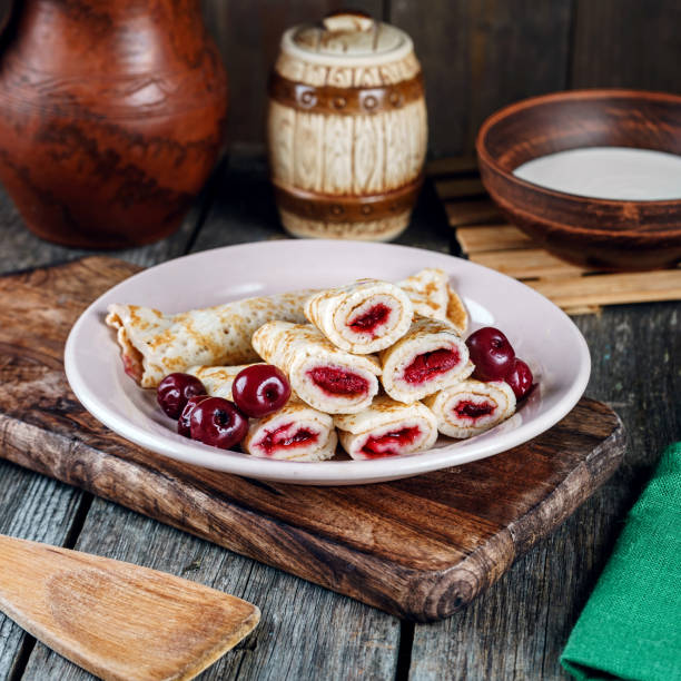 Homemade pancakes with cherries on a wooden table in a rustic style.