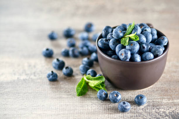 istock Fresh blueberries in bowl with fresh mint leaves on a kitchen table 1388326420