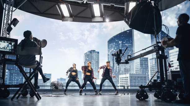music clip studio set: shooting hip hop video dance scene with three professionals dancers performing on stage with big led screen with modern city background. director and cameraman in backstage. - dance recital imagens e fotografias de stock