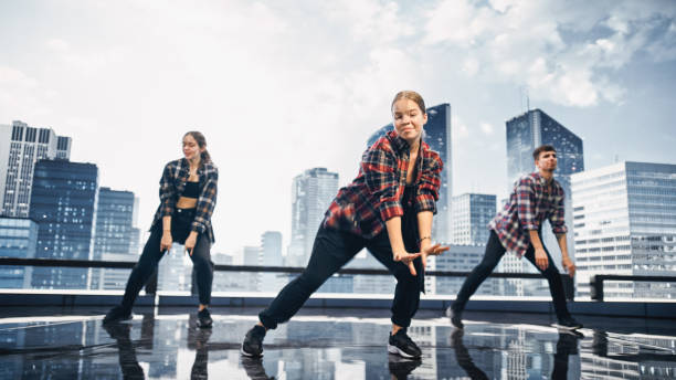 istock Diverse Group of Three Professional Dancers Performing a Hip Hop Dance Routine in Front of a Big Digital Led Wall Screen with Modern City Skyline with Office Skyscrapers in Studio Environment. 1388326556
