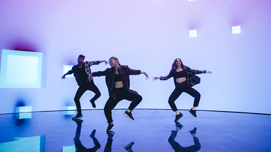 Diverse Group of Three Professional Dancers Performing a Hip Hop Dance Routine in Front of a Big Led Wall Screen with VFX Animation During a Virtual Production in Studio Environment. 105 BPM Song.