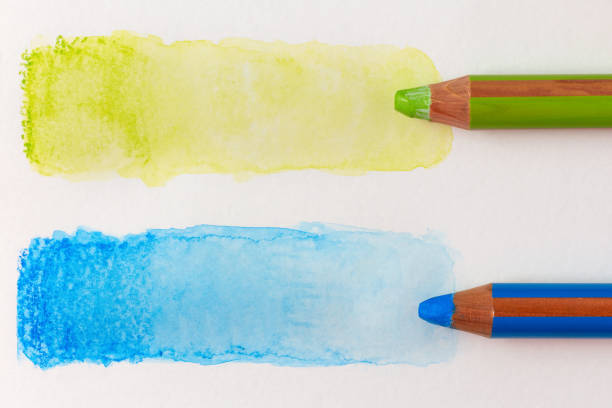 Two large colored green and blue pencils and water-bleached stripes. Testing watercolor pencils