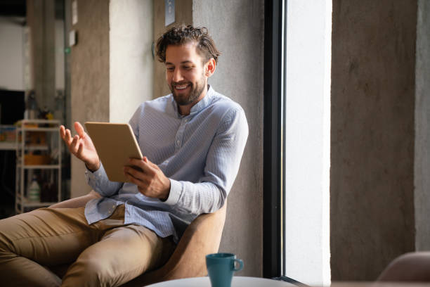 istock Portrait of successful handsome business man using digital tablet in office 1388330311