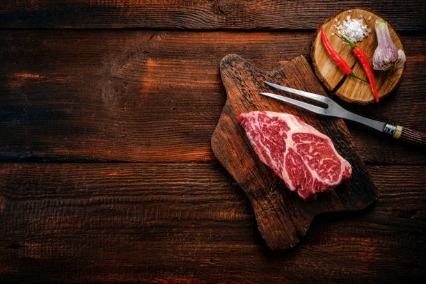 istock Beef shoulder steak on a wooden table with garlic and red pepper, top view and copy space 1388330703