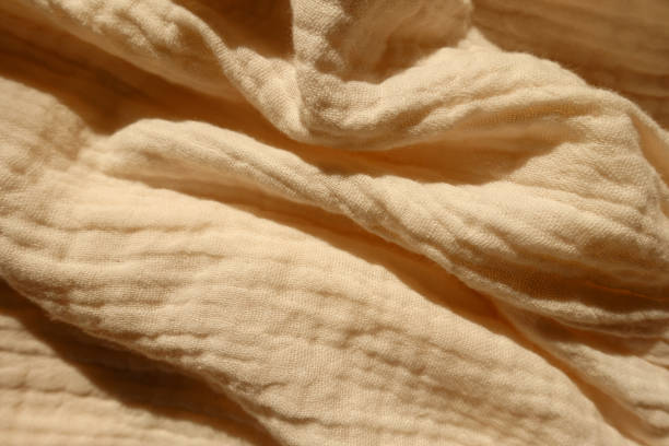 istock Rumpled thin pastel beige cotton muslin fabric 1388333738