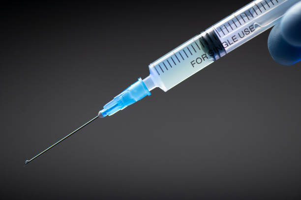 Hand in medical blue glove holding syringe. Grey background. Hand in medical blue glove holding syringe. Grey background. Close-up vaccine vial dose. Medical concept vaccination, fight against virus covid 19 corona virus diabetes epidemiology stock pictures, royalty-free photos & images