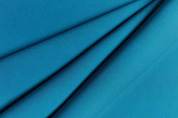 istock Blue crumpled or wavy fabric texture background. Abstract linen cloth soft waves. Gabardine wool fabric. Merino yarn. Smooth elegant luxury cloth texture. Concept for banner or advertisement 1388337751