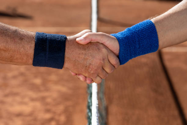 Shaking hands on clay court Close-up of senior tennis players shaking hands on clay court. sweat band stock pictures, royalty-free photos & images