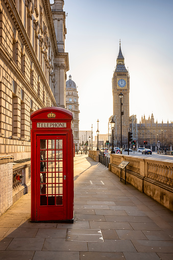 Una clásica cabina telefónica roja frente a la torre del reloj del Big Ben en Londres photo