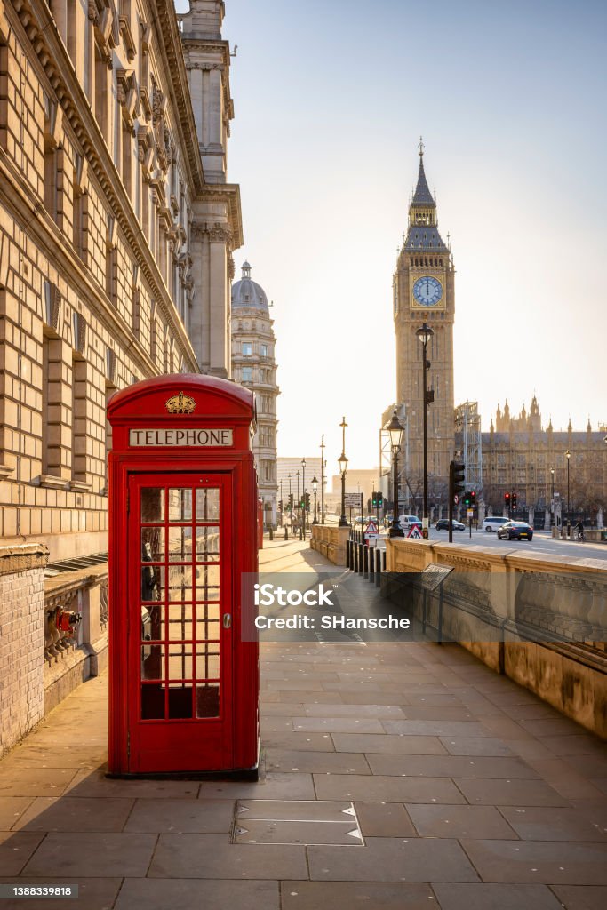 A classic, red telephone booth in front of the Big Ben clocktower in London A classic, red telephone booth in front of the Big Ben clocktower in London, Westminster, during golden sunrise without people London - England Stock Photo