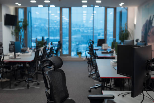 istock Front view of coworking office interior with workplaces, blank picture frame on wall and computer 1388341395