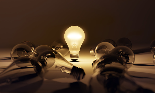 One light bulb glowing among the other dim ones, creative thinking process of innovation, inspiration and new idea