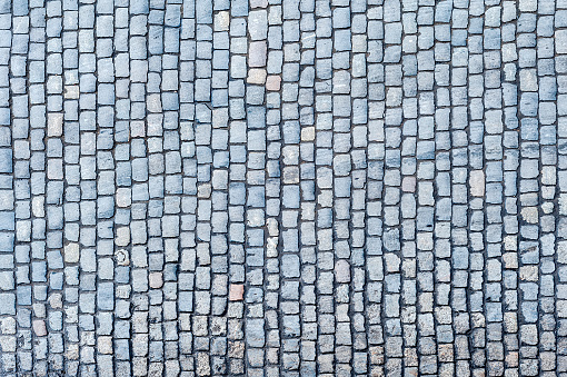 Cobblestone pavement texture background. Top view of stone road. Detail of granite sidewalk taken from above. Old street cobblestones for backdrop. Abstract vintage pavement with rough blocks.