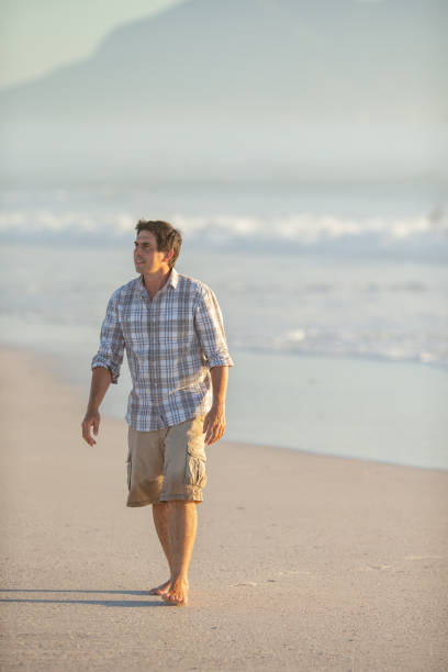 istock Adult man walking barefoot on the beach 1388345282