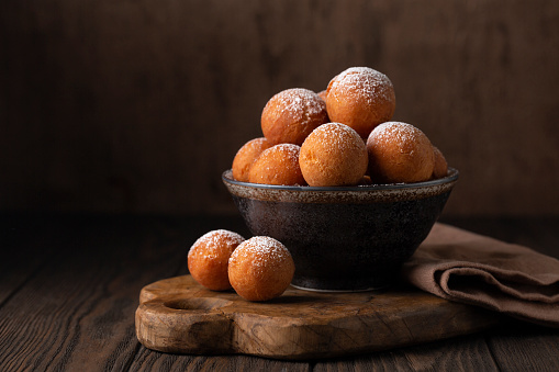 Homemade Donut Holes fried in oil until golden brown and sprinkled with sugar. Castagnole or Favette or Frittelle or Frittole is an Italian fried doughnut. Dark background.