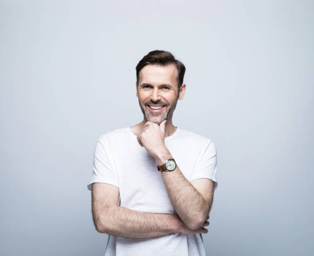 istock Smiling man standing with hand on chin 1388349834