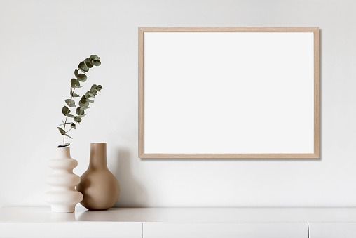 View of modern interior design. Minimalism boho style. Blank white empty frame for painting or poster.