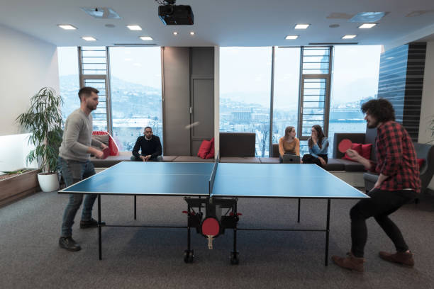 istock Two young start up business man playing ping pong tennis at modern creative office space people group have meeting and brainstorming in background 1388350177