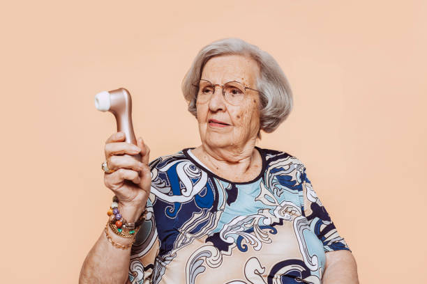 istock Funny doubtful elderly grandmother holding satisfyer dildo 1388351595