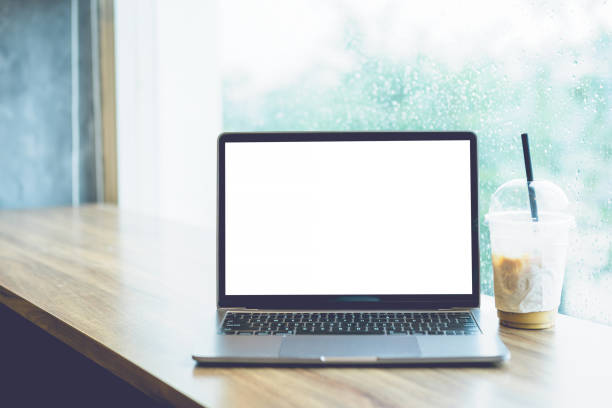 istock Mockup of laptop computer with empty screen with coffee isolate on wooden office desk in coffee shop like the background ,White screen 1388351825