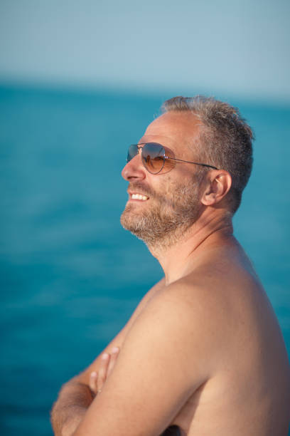 mężczyzna w okularach przeciwsłonecznych cieszący się morską bryzą i światłem słonecznym na wakacjach - clear sky water sports and fitness yacht zdjęcia i obrazy z banku zdjęć