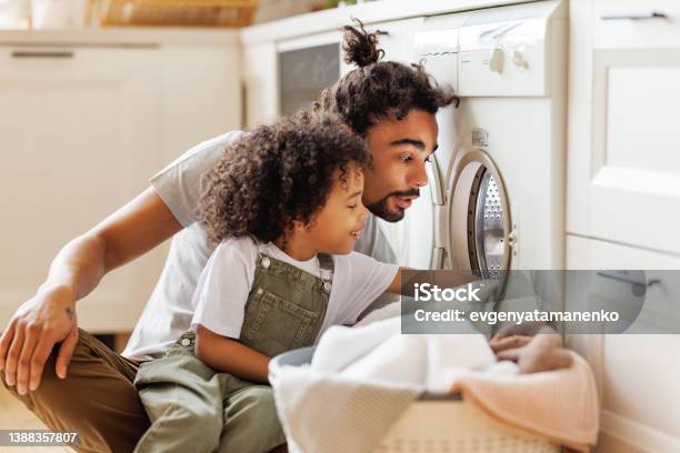 Son Helping Dad To Load Washing Machine Stock Photo - Download Image Now - Laundry, Family, Domestic Life