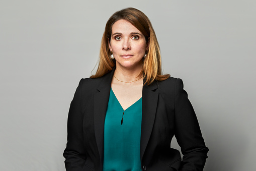 A businesswoman is wearing a suit and with her hands in her pockets.