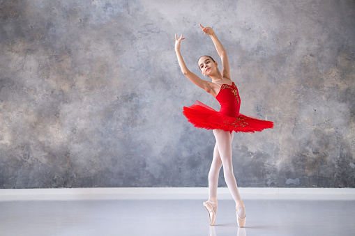 cute little girl dreams of becoming a professional ballerina. girl in bright red tutu on pointe shoes dances in hall. Vocational school student.