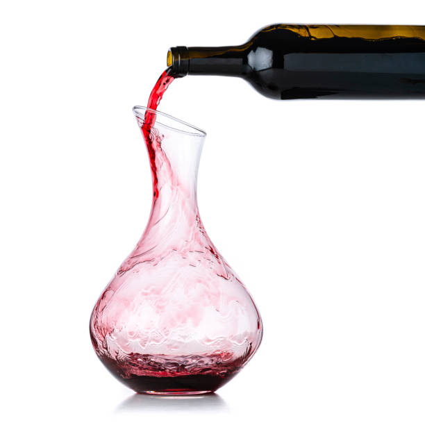 versamento di vino rosso dalla bottiglia nel decanter su fondo bianco - decanter foto e immagini stock