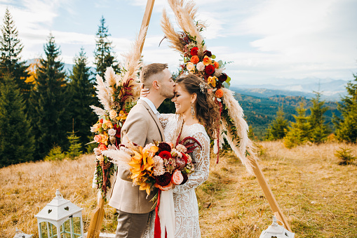 Ceremonia de lujo en las montañas con una vista increíble. El novio besa a su esposa en la frente photo