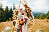 Luxury ceremony at mountains with amazing view. The groom kisses his wife on the forehead