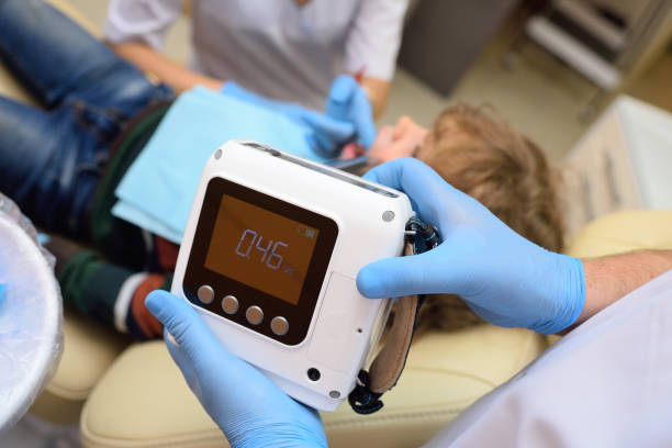 dentista de primer plano con guantes de goma hace una radiografía de los dientes de un paciente infantil en una clínica dental moderna - dentists chair audio fotografías e imágenes de stock