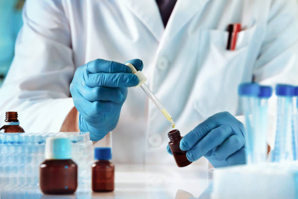 scientist or researcher medical holding test tube and dropping reagent in the biochemistry lab - reagent imagens e fotografias de stock