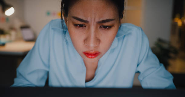 Close up of Young businesswoman working on a laptop sitting at desk in dark office at night. Close up of Young Asian businesswoman working on a laptop sitting at desk in dark office at night. asian blurred vision stock pictures, royalty-free photos & images