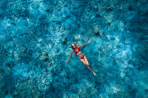 istock Woman lying on crystal water over reef in ocean 1388367837