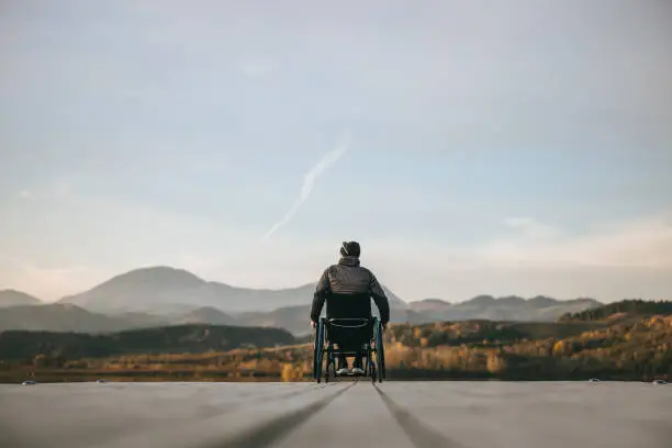 Photo of Paraplegic in wheelchair on pier at sunset