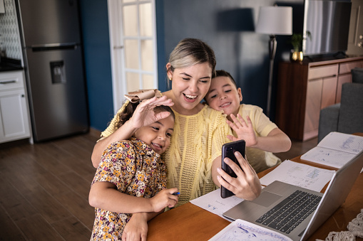 Woman and kids doing a video call on smartphone at home