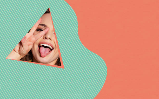 istock Colorful design. Close-up female face with cute and funny expression peeks through triangle in green and orange background 1388371928