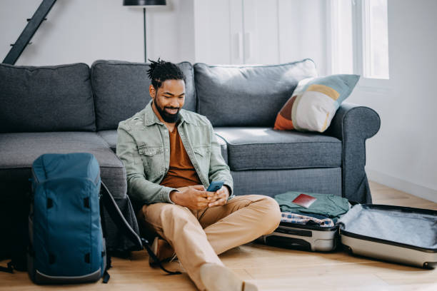 istock Young black man packing suitcase for summer journey on bed 1388372049